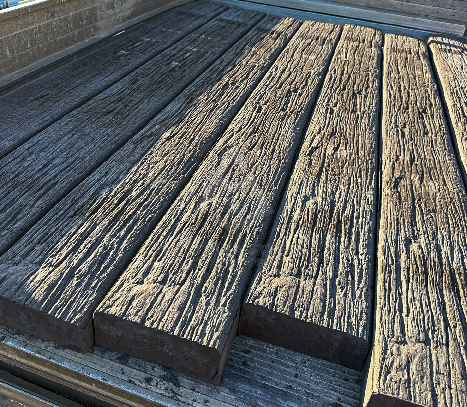 Several long weathered wooden concrete sleepers with a heavily textured, distressed finish arranged on a metal surface.